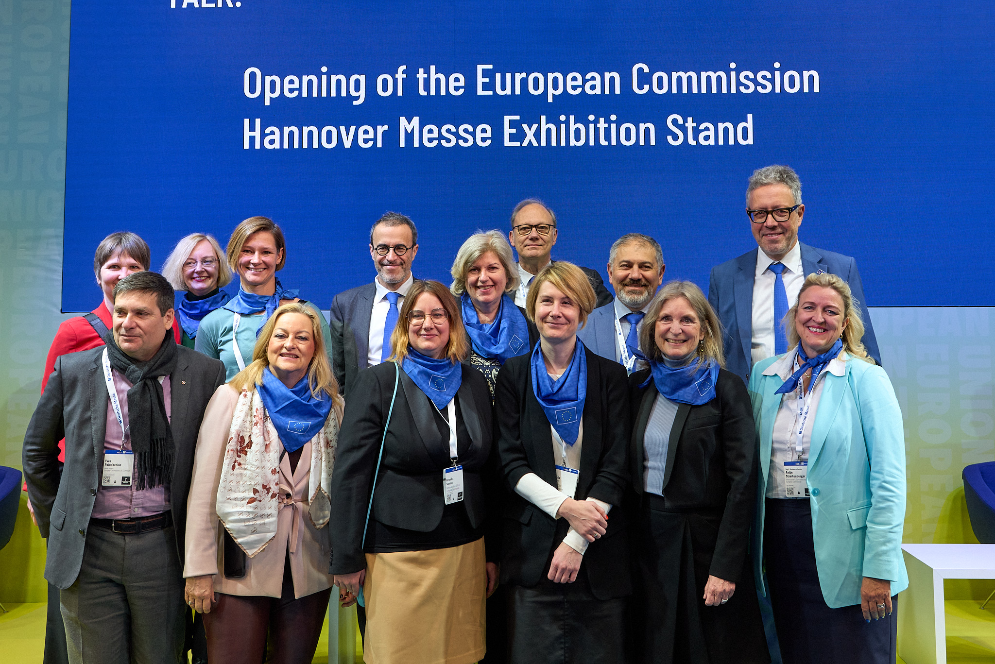 Group photo of 14 Commission staff in front of the EC banner during the opening of the Commission stand